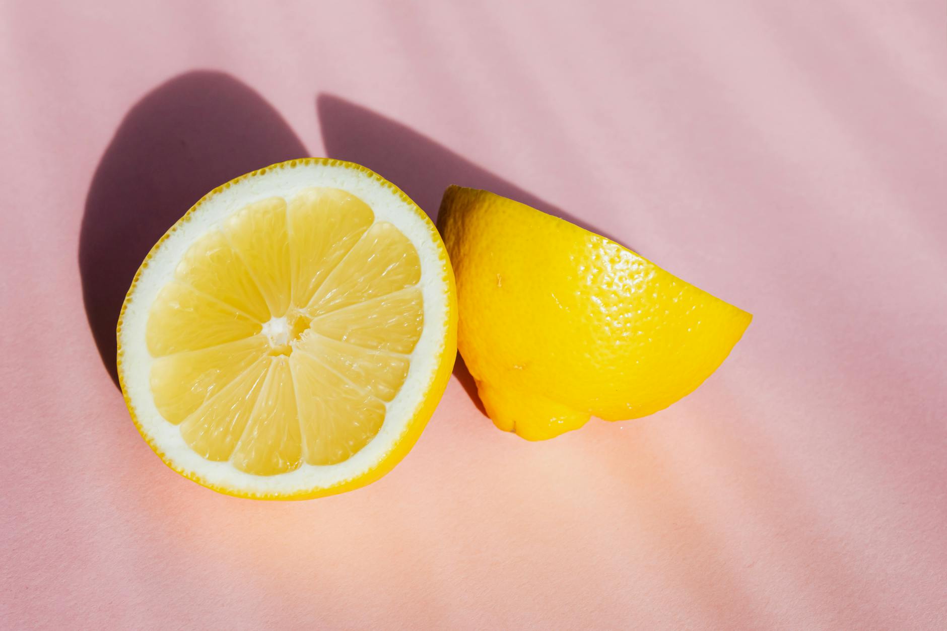 Fresh cut lemon halves on a pink background in sunlight