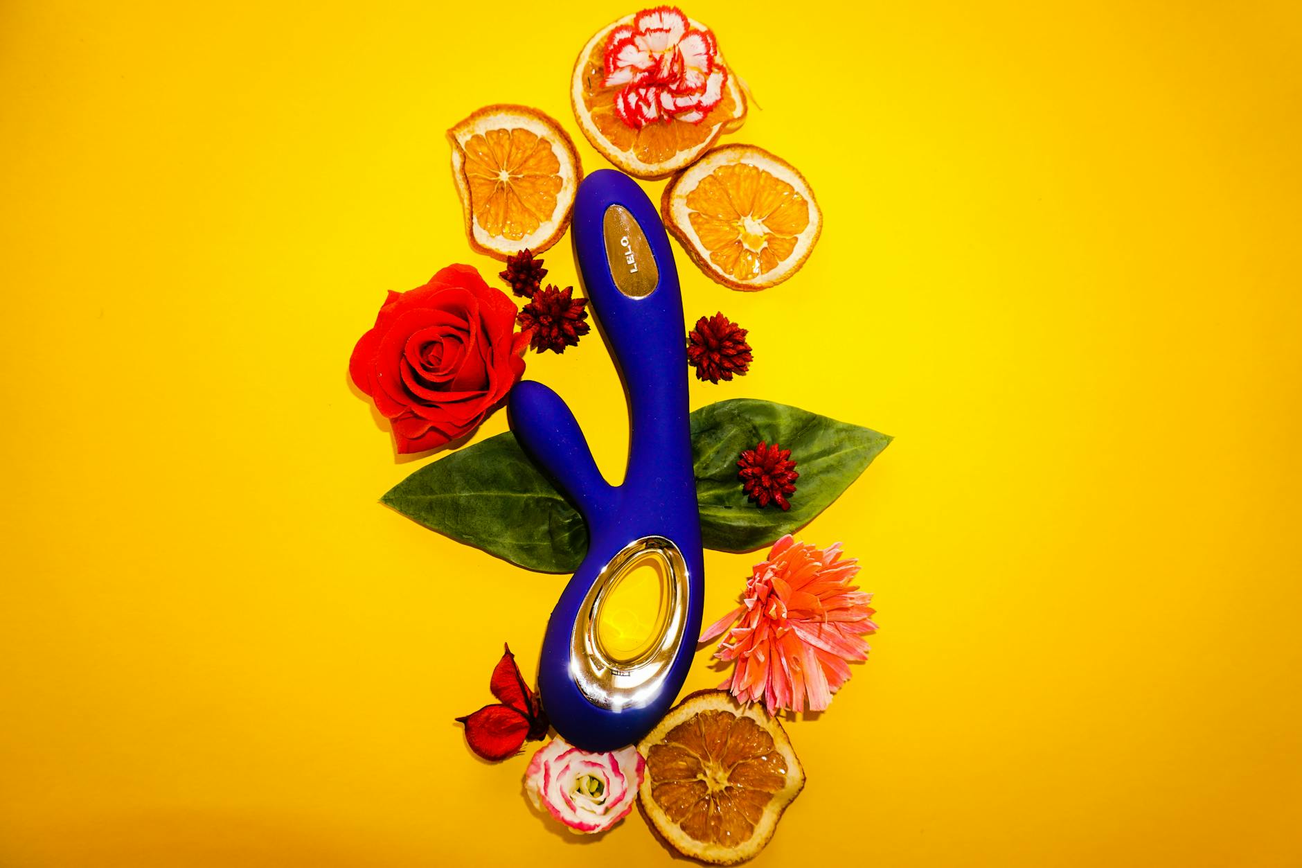A blue lemon vibrator surrounded by citrus and flowers on a bright background