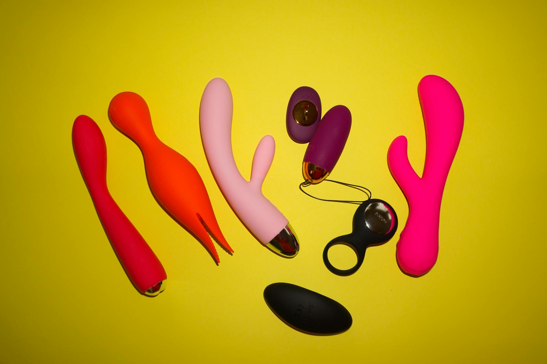 Colorful silicone clitoral vibrators arranged on a bright yellow background